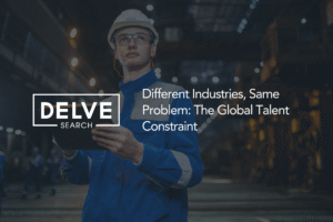 A professional in a hard hat, safety glasses, and a blue work uniform looking at a tablet inside a dimly lit industrial facility. On the right side, the text reads, "Different Industries, Same Problem: The Global Talent Constraint," while the "DELVE SEARCH" logo is displayed on the left within a white rectangular border.